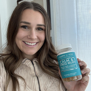 Person holding a supplement bottle labeled 'Be Happy Be You' with a blue label.