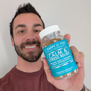 Man holding a bottle labeled 'Be Happy Be You Calm & Stress Relief' against a plain background
