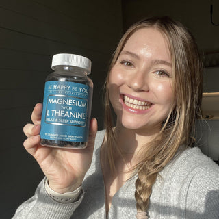 Woman holding a magnesium supplement bottle labeled 'Be Happy Be You'.