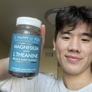Person holding a bottle of 'Be Happy Be You' magnesium with L-theanine gummies.